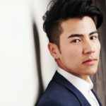 Close-up portrait of a serious Asian man in a formal suit indoors. Modern and professional look.